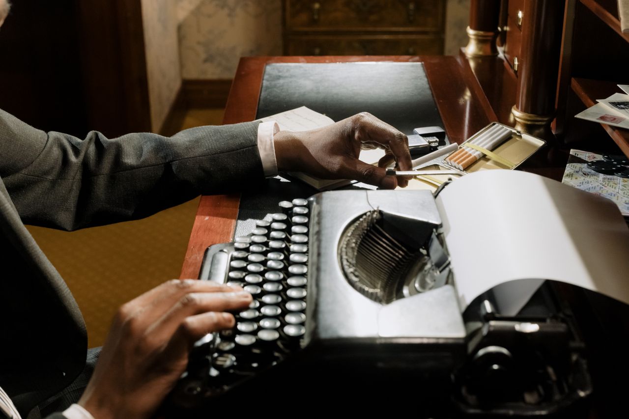 Home A vintage typewriter in a moody, nostalgic workspace with a person typing.